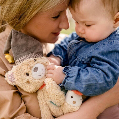 Woman holding a child with a teddy bear and a plush toy